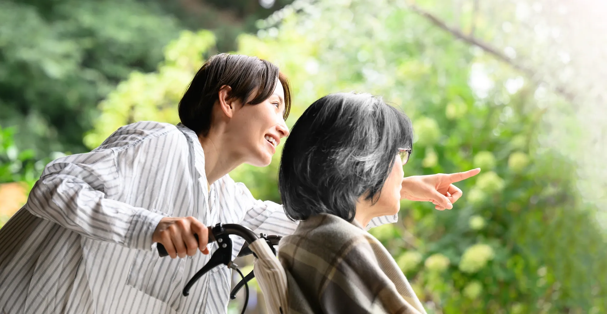 緑の自然のなかで景色を眺める利用者とスタッフ
